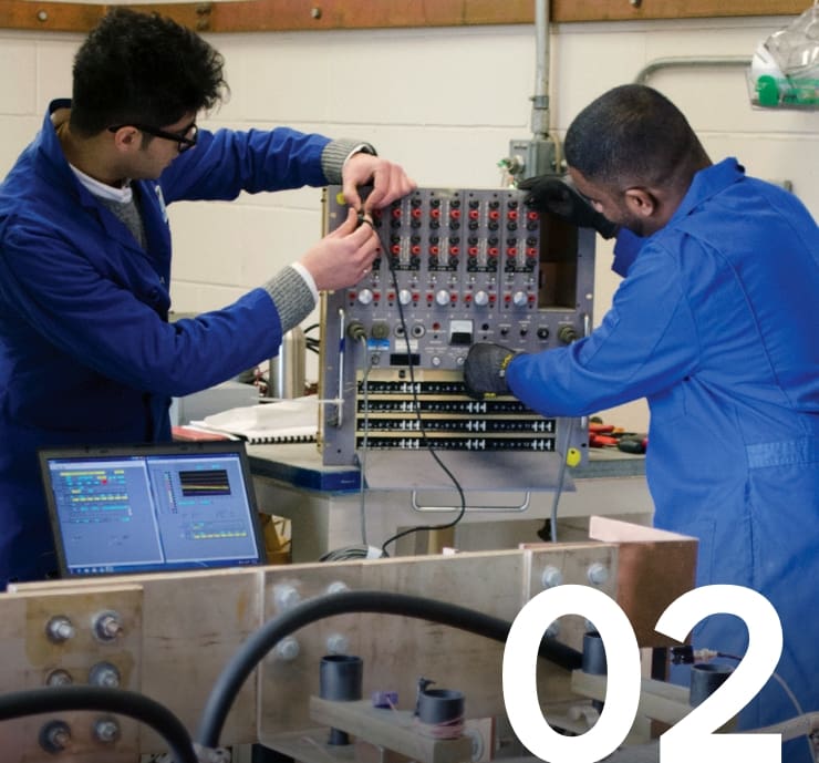 Two engineering technicians in blue lab coats working with industrial testing equipment and diagnostic software in a technical lab, demonstrating hands-on work in power systems and circuit diagnostics.