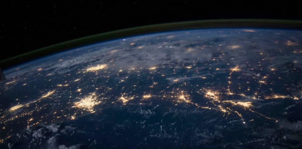 View of Earth from space at night showing illuminated city lights across continents.