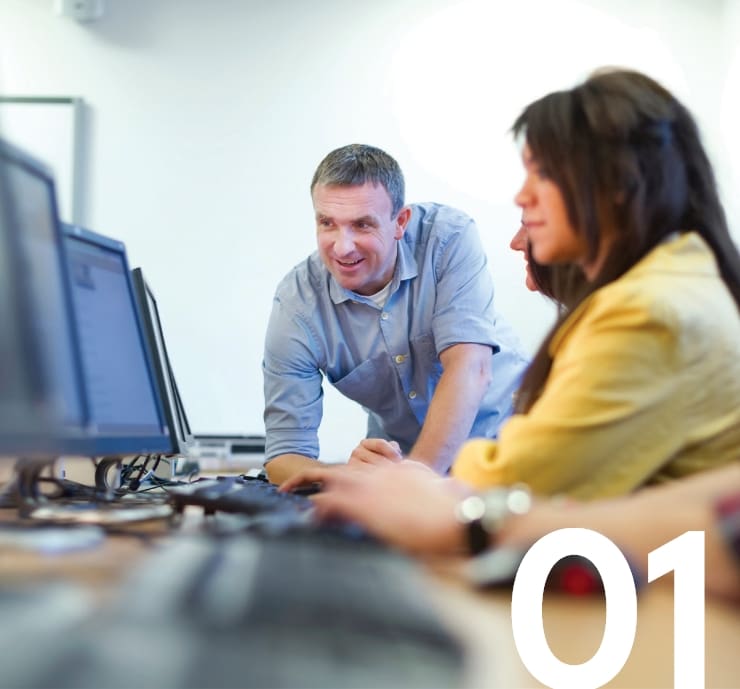 Coworkers collaborate at a computer screen.